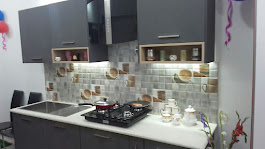 Close-up of modular kitchen countertop with gas hob, under-cabinet lighting, and tile backsplash
